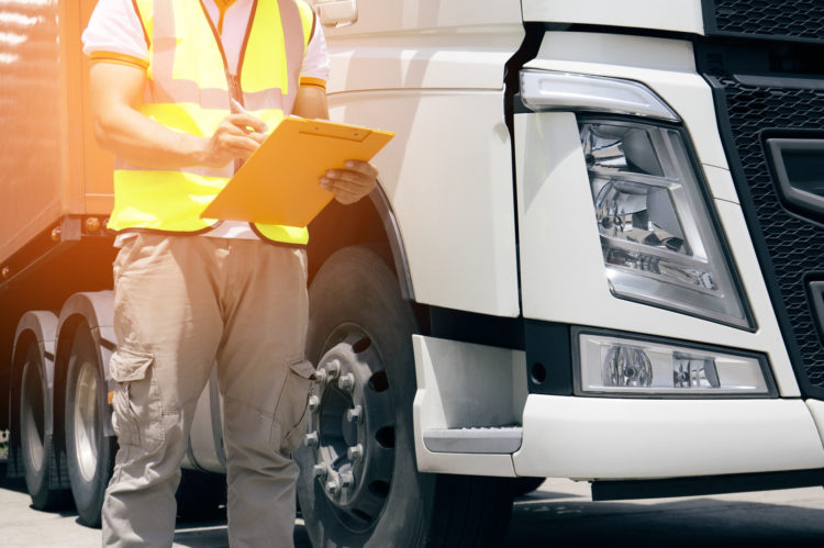 truck driver is inspecting safety of semi truck.